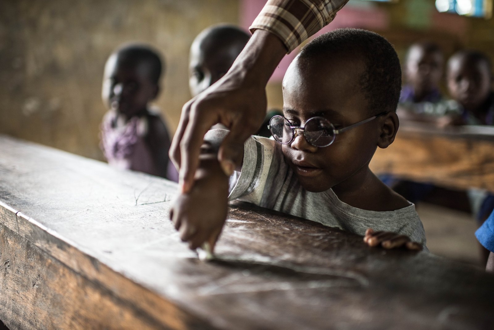 Criscent learns how to write the letter 'A' using white chalk on the desk.